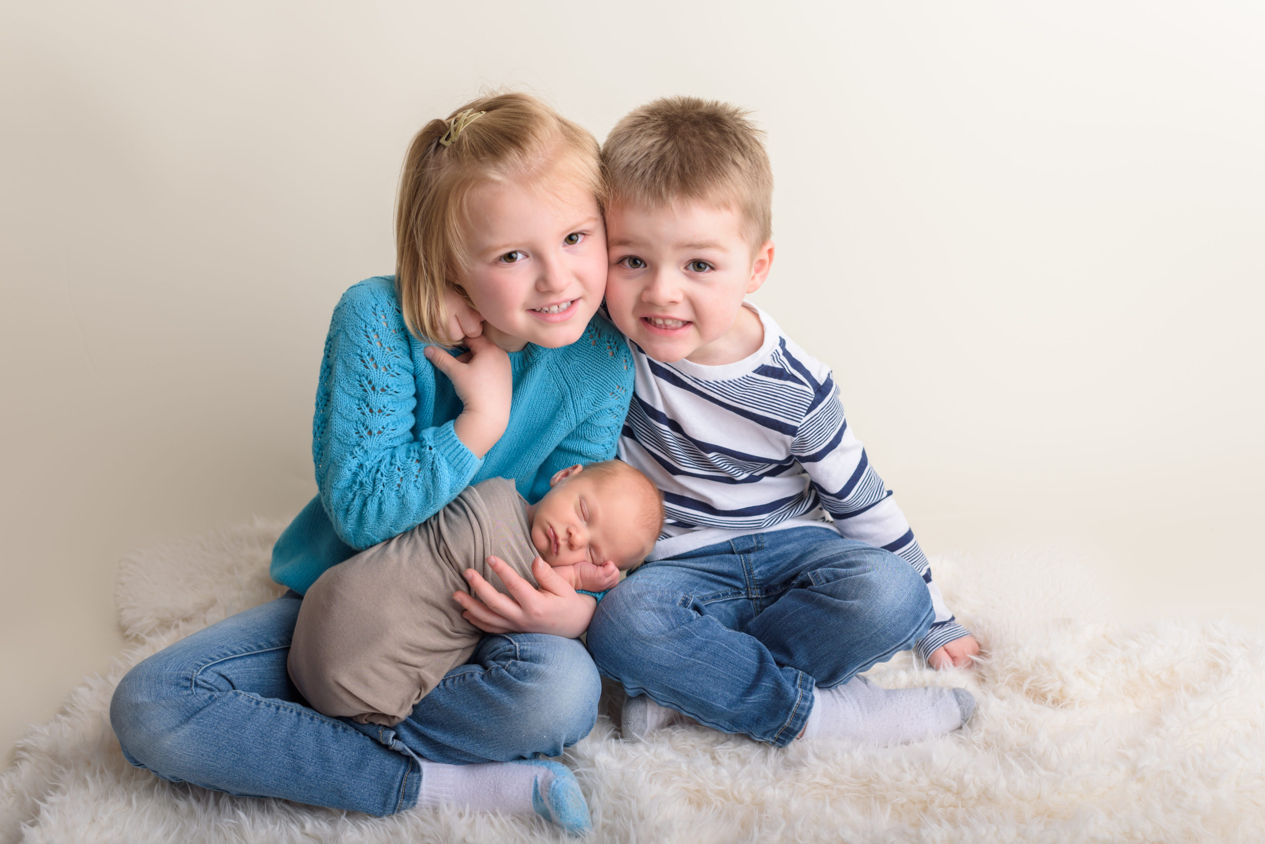 Three siblings smiling at the camera for a Milwaukee newborn session